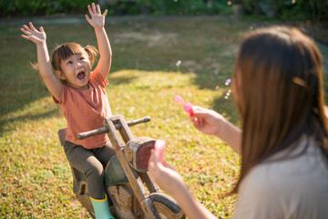 Selective focus, Happy family concept, Mother and lovely daughter blowing soap bubbles in the...