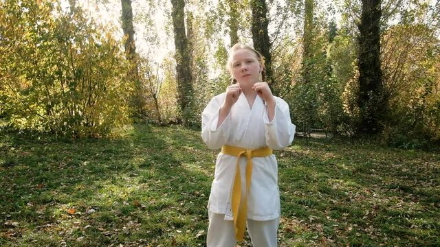 teenager girl 12 years old is engaged in karate outdoors in the park. Healthy lifestyle concept. playing sports. martial arts. Judo, Jiujitsu. bold, strong. does a neck workout. workouts