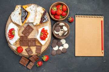 top view cake slices with chocolate bars and cookies on dark background fruit sweet pie