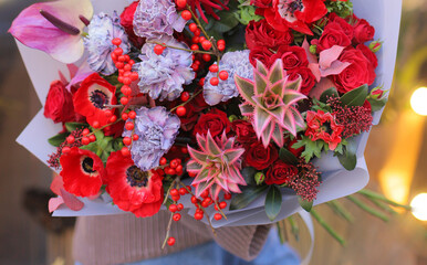 Flower shop. Beautiful bouquet of mixed flowers in color in woman's hands. Work of the florist at a flower shop.  Fresh cut flower.