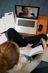 Young woman student having classes, learning online, watching lesson remotely, listening to professor, talking with classmates on video call from home during quarantine
