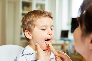 Kinderärztin untersucht Zunge von einem Kind