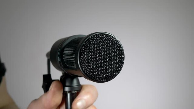 Closeup POV shot of a studio sound engineer man&rsquo;s hands attaching the cable to the rear of a professional microphone on a stand, then placing a pop shield / filter / screen at the front of the mic.