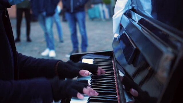 Musician's hands are playing the piano on the street in the city. Creating a pleasant atmosphere using music. A publicly available musical instrument.