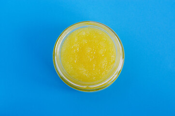 Homemade yellow fruit scrub (bath soak, facial mask) in a small glass jar. Natural beauty treatment and spa recipe. Flat lay, copy space.