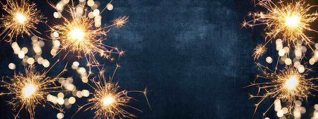 Silvester party New year background banner - sparklers and bokeh lights on blue night sky texture,...
