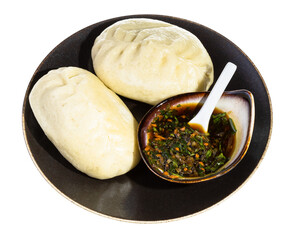 portion of cooked Wang Mandu Pyanse (steamed pie stuffed with vegetable and meat in Korean cuisine) on brown plate with sauce isolated on white background