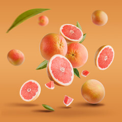 Flying in air fresh ripe whole and cut grapefruit with seeds and leaves isolated on red background.