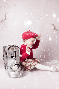 Ni&ntilde;a vestida de rojo con un tren de navidad y nieve