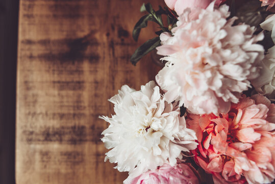 Abundance of Fresh bunch of Peonies Bouquet of different pink colors on rustic background. Card Concept, macro close up image