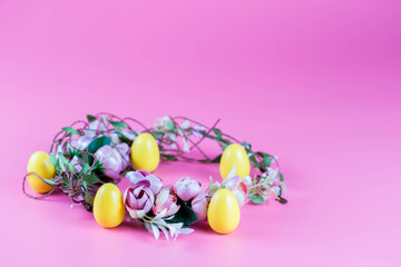 Colored Easter wreath and plastic eggs on a pink background