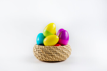 Colorful Plastic Easter Eggs in a wicker basket on white background