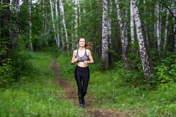 Athletic girl running along the forest path