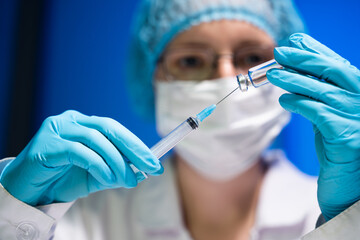 Female doctor about to fill a syringe with medicine