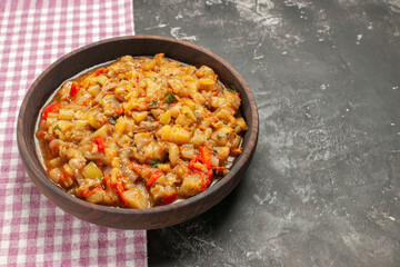 bottom view roasted eggplant salad in bowl on pink white checkered tablecloth on dark background copy space