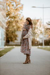 Pregnant woman in dress walking outdoor 