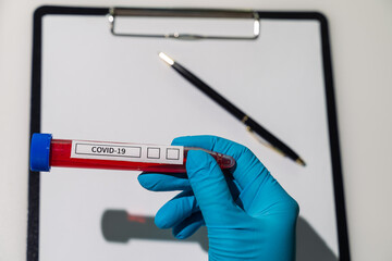 Test tube with blood for analysis for coronavirus on the background of a paper holder on a white background