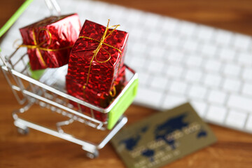 Basket with gifts is on table near keyboard and credit card