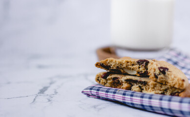 Chocolate cookies on napkin and blur glass of milk background on marble table