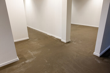 An empty new room with a new clean concrete floor, ready to be painted or made into a synthetic...