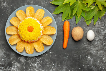 top view of salad with carrot potato and egg and leaves on dark background