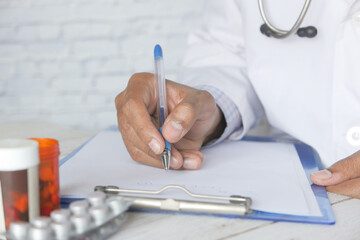doctor hand writing prescription on desk, close up.