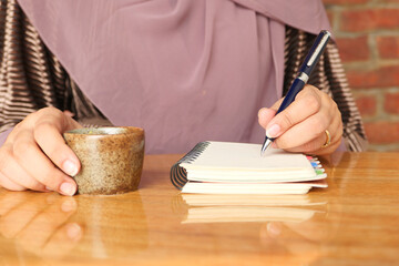 Close up of women hand writing on notepad.