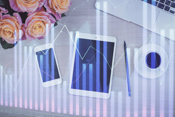 Double exposure of forex graph hologram over desktop with phone. Top view. Mobile trade platform...