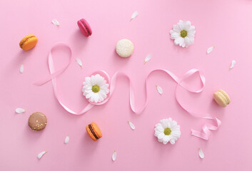 Word love made of pink ribbon with macaroons, white flowers and petals. Top view, pink background. Valentine's day sweet gift concept,holiday, celebration.