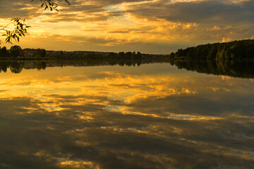 Summer landscape with the setting sun and clouds over the water.