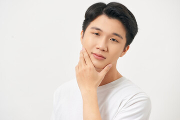 Close up portrait of a young man looking at camera with hand on chin isolated