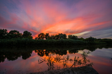 Summer landscape with the setting sun and clouds over the water.