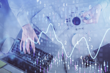 Multi exposure of man's hands typing over computer keyboard and forex graph hologram drawing. Top...