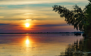 Summer landscape with the setting sun and clouds over the water.
