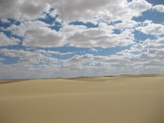 Fototapeta na wymiar Désert égyptien avec ciel bleu et nuages blancs