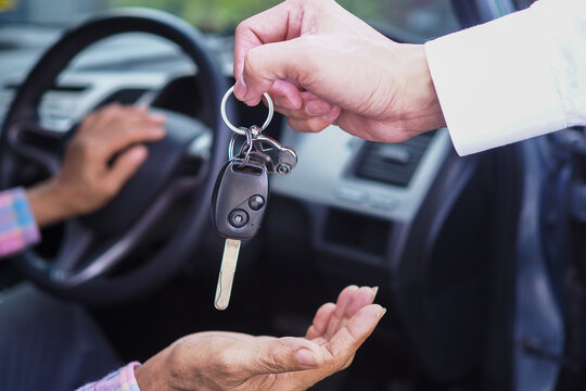 The sales representative is giving the car keys to the new owner in the car. Ideas for renting a car or buying a car.