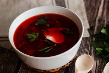 Borsch is a Russian national dish. Soup in a plate on a wooden table. Russian national cuisine. Borscht with sour cream and herbs