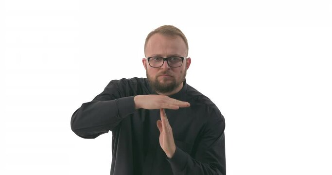 Portrait of young Caucasian priest showing timeout gesture, making T-shape with hands. Isolated on white background