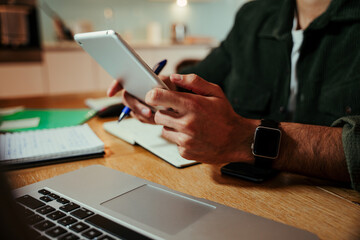 Mixed race businessman working on digital tablet while sitting in home office completing business...