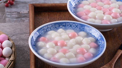 Close up of red and white tangyuan in blue bowl on wooden background for Winter solstice.