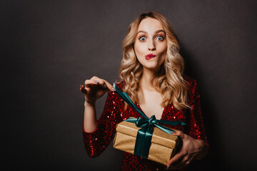 Appealing young woman touching ribbon on new year gift. Half length portrait of blonde birthday...