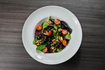 Delicious salad of cherry tomatoes, black olives, walnuts, assorted lettuce, sprouts, and fresh asparagus. Gourmet salad.