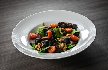 Delicious salad of cherry tomatoes, black olives, walnuts, assorted lettuce, sprouts, and fresh asparagus. Gourmet salad.