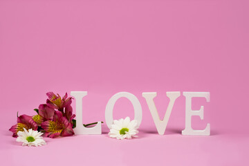 The word love on a pink background with alstroemerias. St.Valentine's card. 