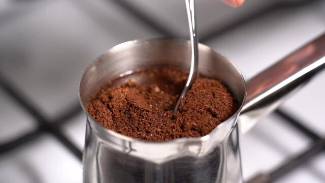 Mixing coffee with teaspoon while preparation in turkish coffee pot