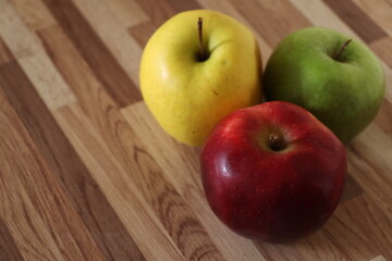 green apple, red apple and whole yellow apple on a table.