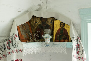 The icon lamp hangs in front of the Iconostasis with icons decorated with embroidered towel and needle lace, next to it lies a bunch of pussy willows for Easter.