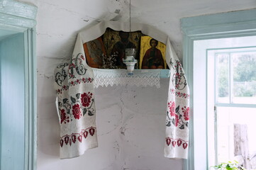 The icon lamp hangs in front of the Iconostasis with icons next to it lies a bunch of pussy willows for Easter in the corner of the village hut.