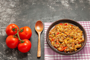 top view roasted eggplant salad in bowl a wooden spoon tomatoes on dark background