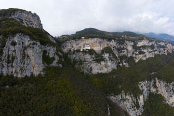 Aerial view of the church on the sheer cliff. The unique Sanctuary Madonna della Corona church in the rock. The sanctuary is high in the mountains of Italy. Italian church at high altitude in the Alps